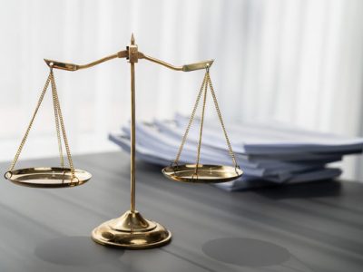 Shiny golden balanced scale and pile of legal paper on desk in lawyer office as concept justice and legal symbol. Scale balance for righteous and equality judgment by lawyer and attorney. equility